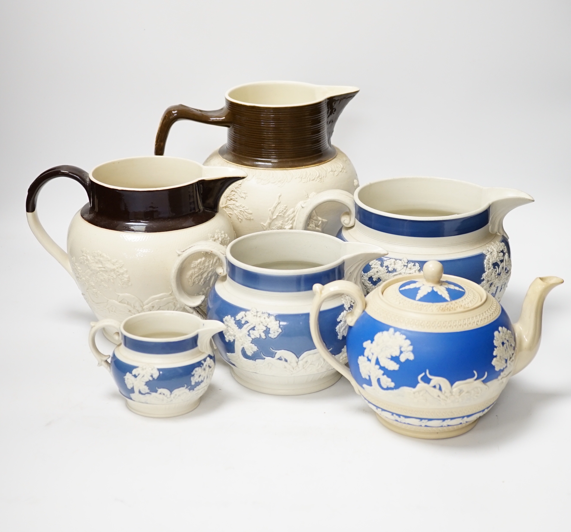 A group of Staffordshire white stonewares: five jugs and a teapot, including Adams, tallest jug 21cm high